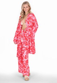 Rózsaszín és piros virágmintás kimono és nadrág szett könnyű anyagból, széles ujjakkal és laza szabással, platform szandálokkal párosítva.