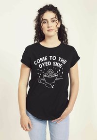 Camiseta de algodón negra con el texto "VEN AL LADO TIÑIDO" y un gráfico de un cuenco de tinte y cuchara, de mangas cortas y ajuste relajado.