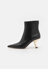 Bottine en cuir noir avec un bout pointu et un talon métallique doré. Texture lisse avec un design minimaliste, sans motifs visibles.