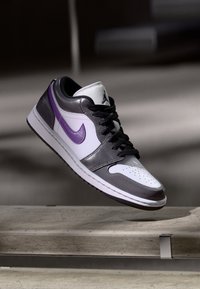 Nike Air Jordan 1 bateliai turi baltą odinį priekinį bandą, pilkas odines šonines dalis ir purpurinį swoosh, su juodais raišteliais ir guminiu padu.