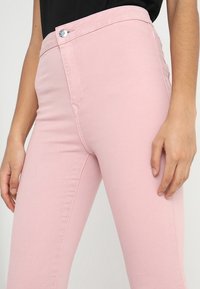 Jeans slim-fit de color rosa claro, elaborados con una mezcla de algodón, que cuentan con un cierre delantero de botón, pasadores para cinturón y sutiles detalles de costura.