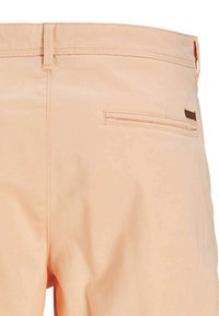 Pantaloni beige con una singola tasca a filetto posteriore e passanti per cintura, mostrati dall'area posteriore della vita.