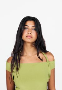 Haut vert à épaules dénudées avec un décolleté carré et des fines bretelles, présentant une texture lisse et mate ainsi qu'un design ajusté.