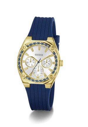 Auksinis ir mėlynas Guess riešo laikrodis su mėlynu tekstūruotu silikoniniu dirželiu, balto ciferblato, trimis subciferblatais bei auksiniais valandų žymekliais ir rodyklėmis.