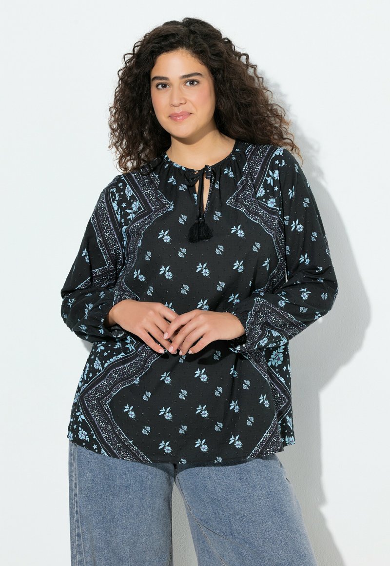 Blusa negra con estampado floral en azul claro, con escote redondo, detalle de lazo y mangas largas con puños elásticos. Tejido texturizado.