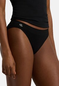 Czarna bawełniana bielizna bikini z miękkim pasem, z małym białym logo na przodzie. Gładka faktura i dopasowany krój.