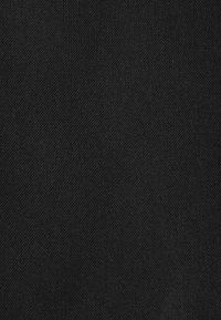 Texture de tissu noir avec motif de sergé diagonal, montrant des variations subtiles dans l'ombrage et les détails des fibres.