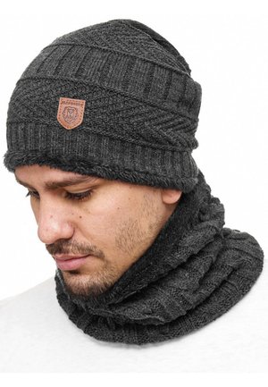Grå strikket beanie med et struktureret mønster og en faux fur foring, ledsaget af et matchende grå infinity tørklæde, begge med et logo-patch.