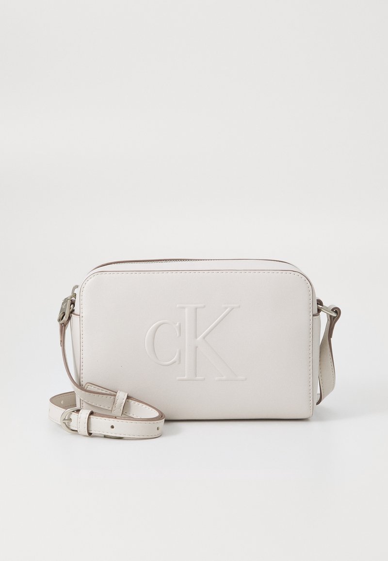 Světle béžová crossbody taška vyrobená z hladké kůže. Nabízí embosované logo "cK", zipové uzavření a nastavitelný popruh.