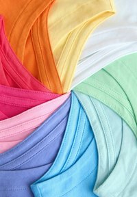 Ułożone w okrąg kolorowe bawełniane maseczki do twarzy, pokazujące przeszywane krawędzie i pętle na uszy w pastelowych i jaskrawych kolorach.