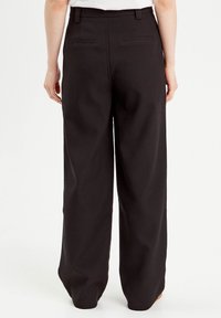Pantalon noir à jambes larges avec une texture lisse, doté d'une taille mi-haute, de passants de ceinture et de deux poches arrière.