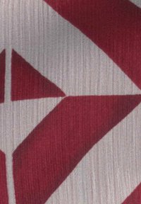 Formes géométriques rouges et blanches avec des triangles et des formes angulaires sur un fond de tissu texturé.