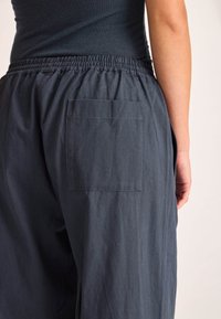 I pantaloni grigi scuri presentano una cintura elastica, una tasca posteriore singola e un tessuto morbido e testurizzato con un design a vestibilità comoda.