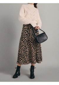 Gehaakte crèmekleurige trui met hoge hals, gecombineerd met een zwart en beige luipaardprint midi-rok. Gestyled met zwarte veterschoenen en een getextureerde tas.
