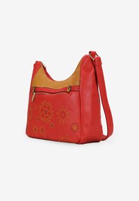 Bolso de hombro de cuero rojo con una sección superior marrón, que presenta diseños florales en relieve dorados y un bolsillo con cremallera en la parte delantera. Incluye una correa ajustable.