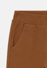 Braune gerippte Stoffhosen mit strukturierten Oberflächen, ausgestattet mit einem breiten Bund und Seitentaschen für zusätzliche Funktionalität.