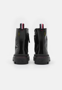 Svart lackläder anklar stövlar med rundad tå. Har dubbla dragkedjor, röda och blå tab-förstärkningar, samt slitstarka svarta gummisulor.