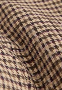 Woven fabric with a houndstooth pattern in beige, brown, and hints of purple. Soft texture with a smooth, slightly raised finish.