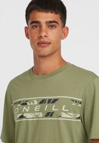 Camiseta de algodón verde oliva con un estampado gráfico en blanco y negro, cuello redondo y un diseño de corte relajado.