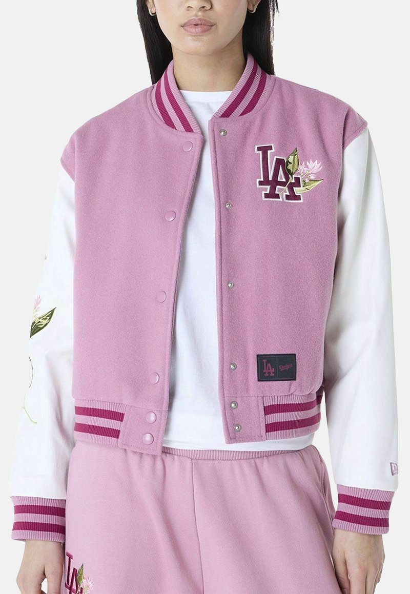 Veste varsity en polaire rose avec des poignets et un col côtelés rayés ; présente un logo LA brodé et des détails floraux. Fermeture à boutons sur le devant.