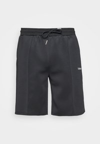 Pantalones cortos deportivos negros con cinturilla elástica, cordón y detalle en las costuras laterales. Presenta un pequeño logo blanco. Textura suave.