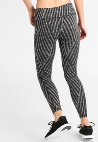 Legginsy w czarno-szary wzór z geometrycznym designem, wykonane z elastycznej tkaniny, z wysokim stanem i dopasowanym krojem.