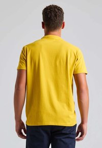 T-shirt en coton jaune avec un col rond et des manches courtes, vue de dos. Texture lisse, design décontracté et sans motifs visibles.