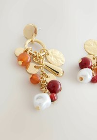 Gold-tone earrings featuring hanging beads in orange, red, and white, with textured circular accents and a mixed metal design.