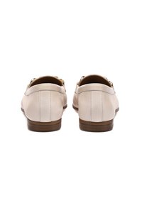 Hellbeige Lederchuhe mit einem niedrigen braunen Absatz, die eine glatte Oberfläche und dezente Steppdetails auf der Rückseite aufweisen. Akzente aus goldfarbenem Metall.