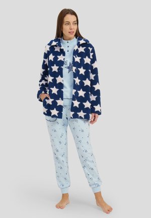 Chaqueta de forro polar en color marino con un patrón de estrellas blancas, combinada con pantalones azul claro que presentan un sutil patrón de copos de nieve y puños acanalados.
