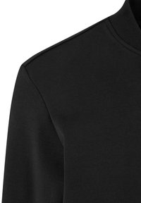 T-shirt noir à manches longues et col rond montrant l'épaule, le haut de la manche et l'encolure avec des détails de couture visibles.