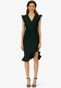 Dunkelgrünes Kleid mit V-Ausschnitt, kurzen Ärmeln und rüschigem Saum. Aus glattem Stoff gefertigt, betont das enganliegende Design die Figur mit einem hohen Schlitz.