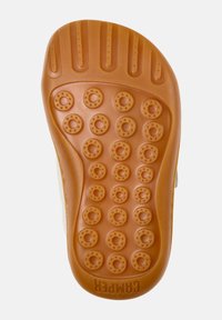 Gummisohle in Beige, mit kreisförmigen Griffmustern und horizontalen Rillen für Traktion, mit dezentem Branding in der Nähe des Randes.