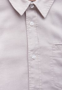 Ljust färgad kortärmad skjorta i ett texturerat tyg med ett litet mönster, med en knäppning och en bröstficka.