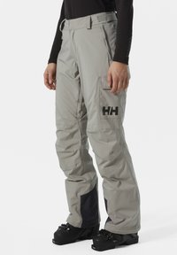 Grau Skihosen mit geradem Schnitt, Cargo-Tasche und schwarzem Logo. Merkmale sind Kontrastpaneele und ein verstärkter Saum für Langlebigkeit.