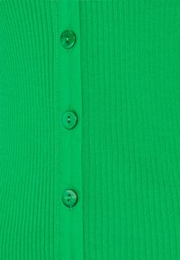 Cardigan verde a coste con cinque bottoni verdi al centro, caratterizzato da una texture liscia e un design a tinta unita.