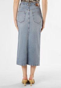 Light blue denim midi skirt with a straight cut, back pockets, and a stitched hem. Features a visible waistband and tag at the back.