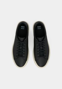 Sorte lærersneakers med teksturert finish, med flat snøring og kremfargede gummisåler. Embossert merkelo Go inside.