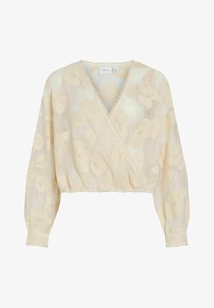 Kermanvärinen kietaisupaita, jossa on kukkakuvioinen pitsikerros ja pitkät hihat. Pääntiessä on aaltoileva reuna ja helmassa elastinen resori.