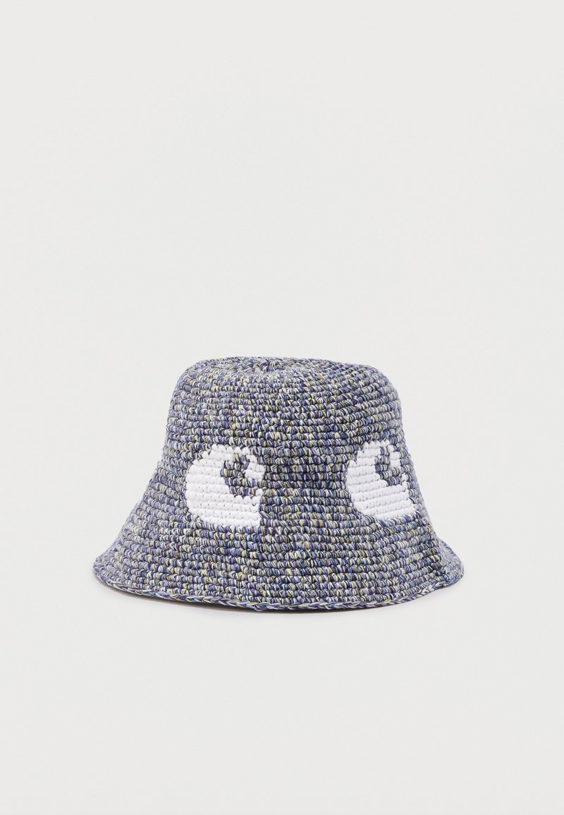 Chapeau seau au crochet bleu et blanc avec deux motifs en spirale de coquillages blancs sur les côtés, sur un fond uni.