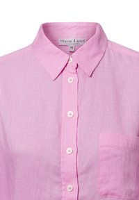 Light pink collared shirt made of textured fabric, featuring a front button placket and a single chest pocket.
