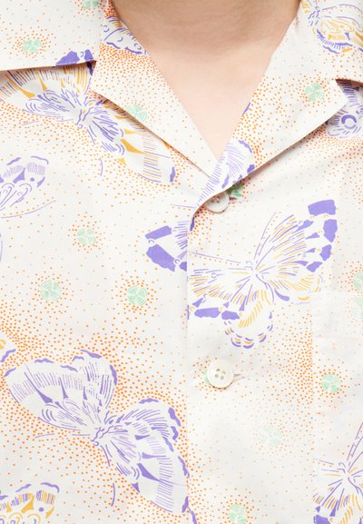 Col de chemise et boutons avec tissu blanc présentant des papillons violets et jaunes ainsi que de petits motifs ponctués orange et verts.