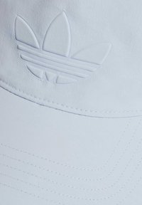 Světle modrá baseballová čepice vyrobená z měkké látky, s embosovaným logem tří listů a jemným prošíváním na okraji.