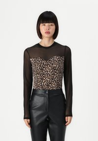 Felpa a maniche lunghe con sovrapposizione trasparente nera e un corpetto con stampa leopardata a scollo a cuore. Abbinata a pantaloni in pelle nera.
