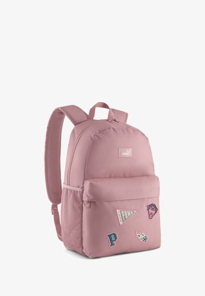 Rosa Puma-Rucksack mit verstellbaren Trägern, seitlicher Netztasche, vorderer Reißverschlusstasche und dekorativen Aufnähern, darunter ein Panther und ein Fußball.