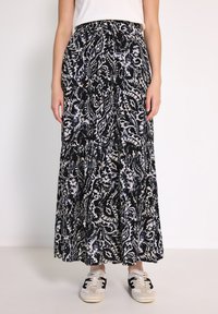Černá maxi sukně s bílým a modrým paisley vzorem, vyrobená z lehkého materiálu. Elastický pas a volánkový design. Kombinováno s teniskami.