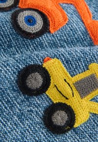 Hímzett minta narancssárga és sárga járművekkel, texturált kék farmeranyagon. Fontos részletek közé tartoznak a kontrasztos fekete kerekek és a szürke díszítések.