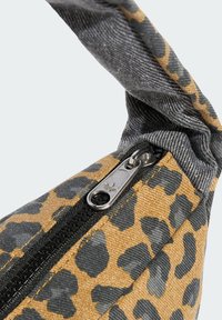 En leopardmønstrets stoffveske med en grå denimstropp, sølvglidelås, og en teksturert overflate med svarte aksenter.