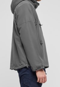 Grå huva jacka med lös passform, har en framficka, justerbara ärmslut och en mjuk, vattenavvisande yta.