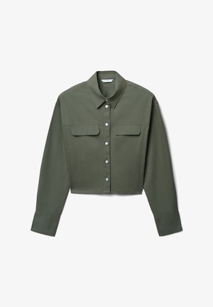 Chemise boutonnée à manches longues, cropped, couleur vert olive, avec un col pointu et deux poches à rabat sur la poitrine, posée à plat sur un fond blanc.